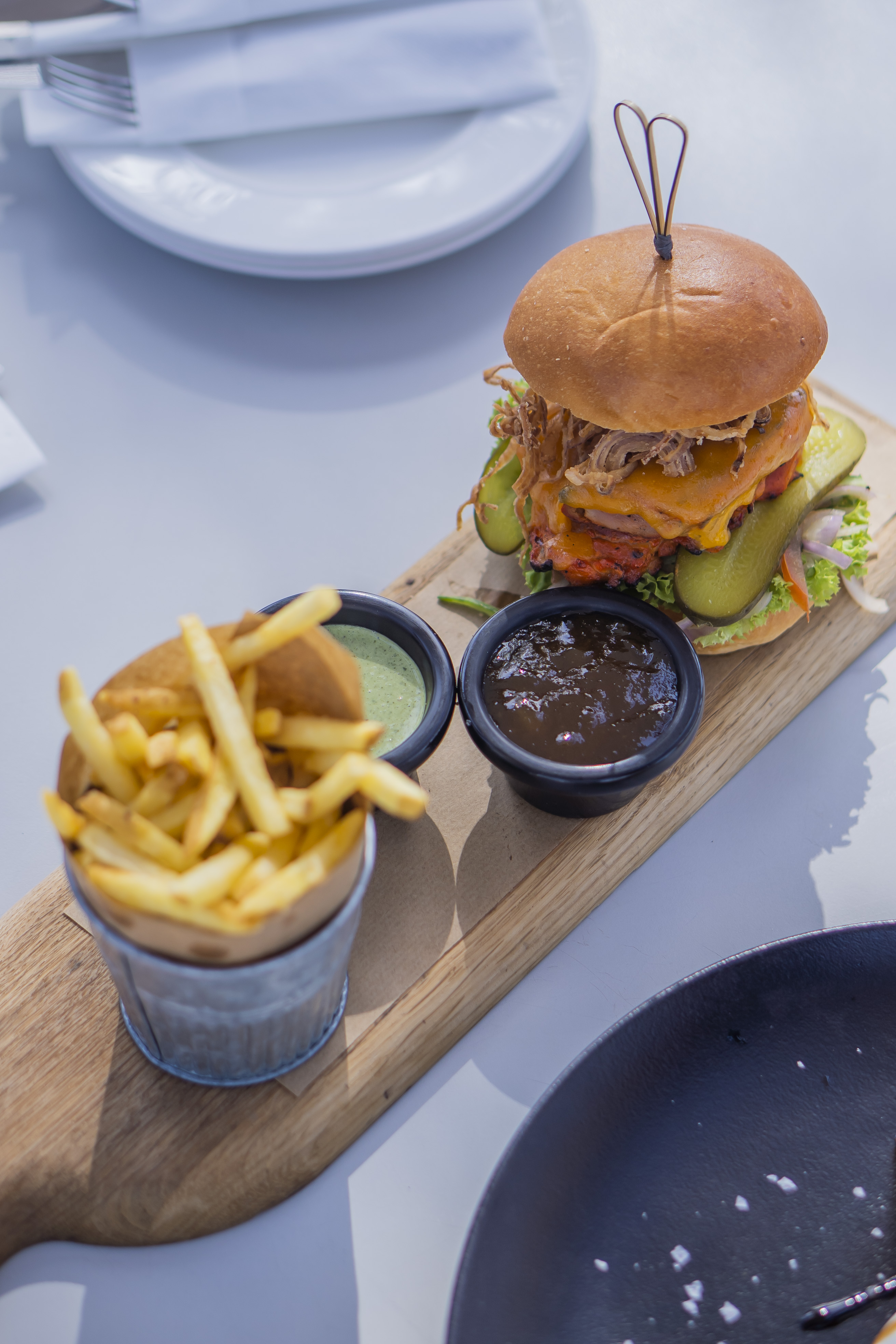 Juicy burger and crispy chips served on a rustic wooden board at Saadiyat Beach Club, perfect for casual dining.